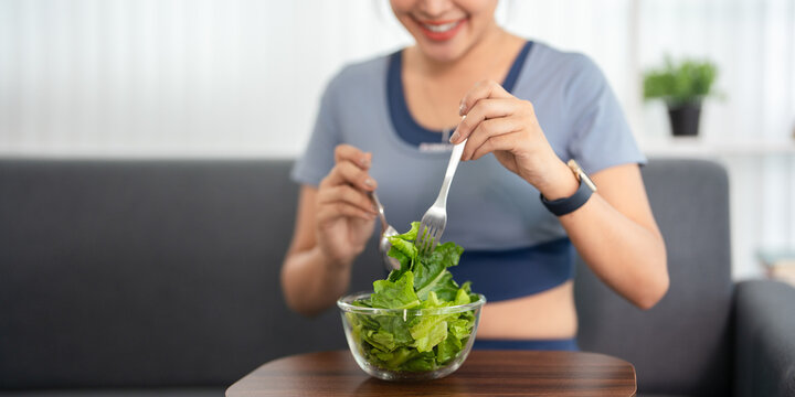 Healthy young woman having salad after work out at home, sport and healthy food lifestyle concept.