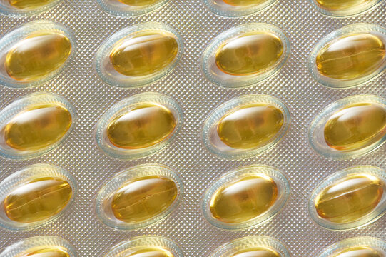 Yellow softgel Omega capsules in silver blister pack closeup