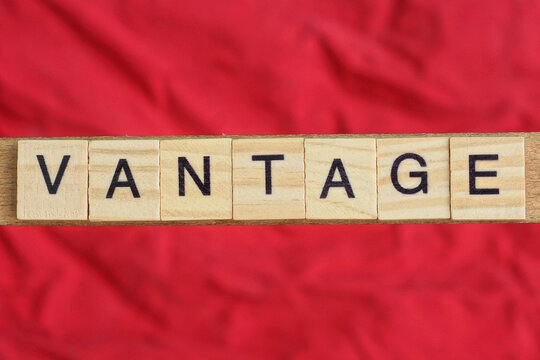 text the word vantage from gray wooden small letters with black font on an red table