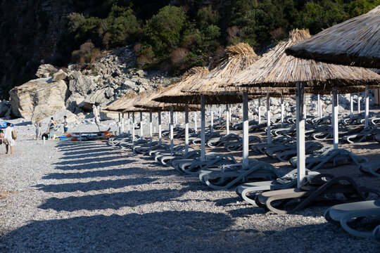 beach with rocky cliffs and white umbrellas in a relaxed, serene coastal landscape perspective period