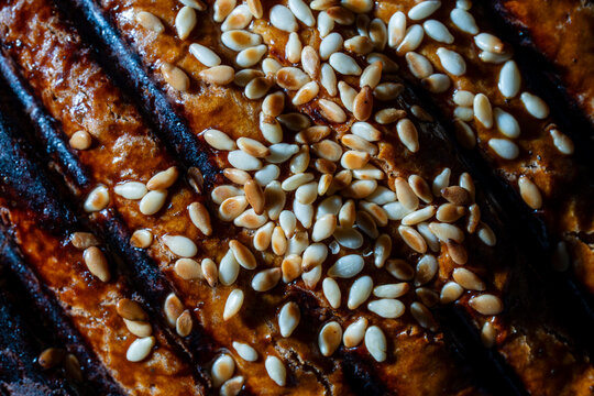 Closeup of baked bread crust with sesame seeds. Macro texture of golden brown crispy homemade bread crust with deep slashes and sprinkled toasted sesame seeds filling the frame