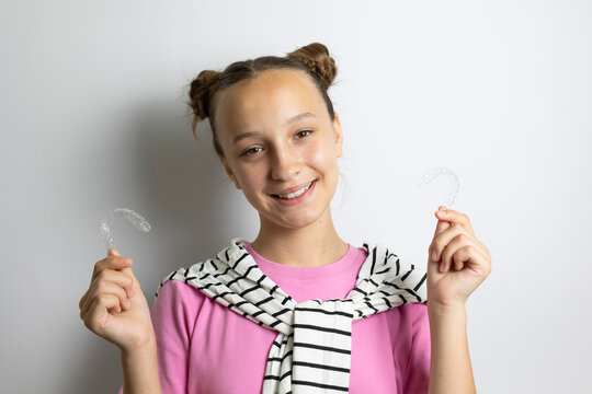 Teenage girl Teenage girl smiling while holding a transparent dental aligner for teeth straightening. Adolescent orthodontics, invisible braces, dental care and oral health concept.holding clear denta
