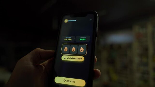 Hand holding smartphone with slot machine app showing jackpot win in the dark