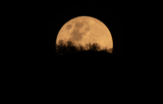 View of the full moon rising behind the silhouette of Chastelets Peaks in Silvaplana, Grisons, Switzerland.