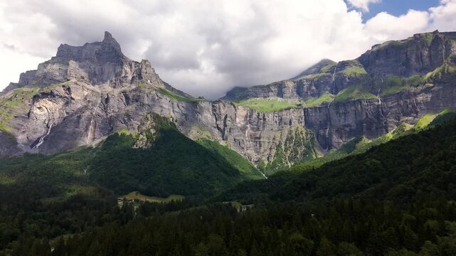 Cirque du Fer-a-Cheval, Sixt-Fer-a-Cheval, Haute-Savoie, France, revealing towering limestone cliffs, alpine forest, mountain cirque and rugged peaks beneath dramatic clouds, drone establishing shot.
