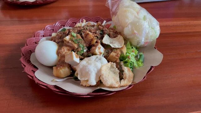 Close up look of delicious lotek or gado gado with crackers on woven plate