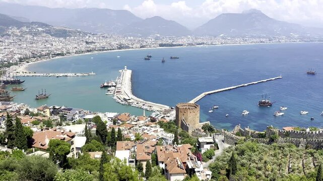 Scenic panoramic high angle view of the historic Red Tower Kizil Kule and harbor with tourist ships in Alanya, Turkey