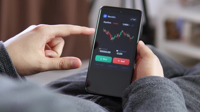 Investor studies a volatile stock chart on a smartphone, reflecting mobile trading, market uncertainty and growing demand for real-time financial control.