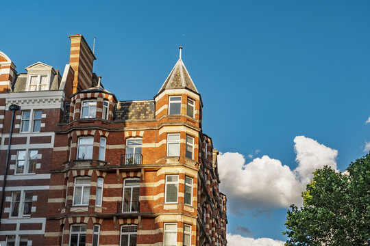 View of the historic red brick architecture with white stone detailing and a distinctive corner turret in Westminster, London, England, United Kingdom.