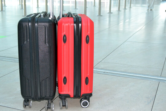 Pair of rolling suitcases luggage at airport terminal floor close-up for travel background and baggage concept