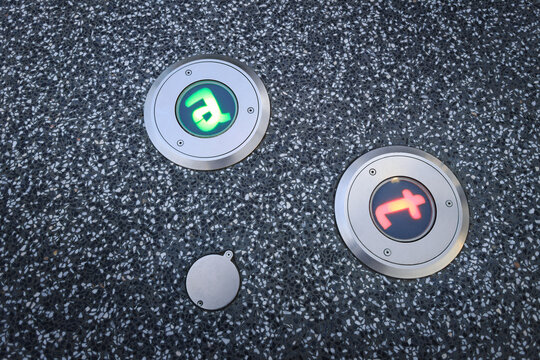 Circular symbols embedded into the ground represent adenine (a) and thymine (t), two of the four primary chemical bases that form DNA, Pedestrian direction lights embedded in the walkway