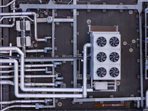 Aerial view of a data center rooftop featuring industrial cooling units, ventilation pipes, and metallic ductwork in Gdansk, Poland.