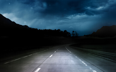 Obraz premium dark night road through forest and mountains, rain and storm