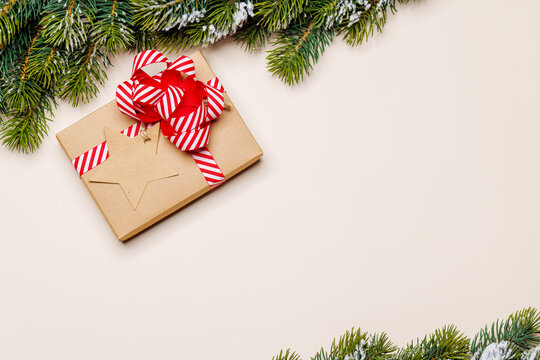 Gift box on snowy fir branches on beige background