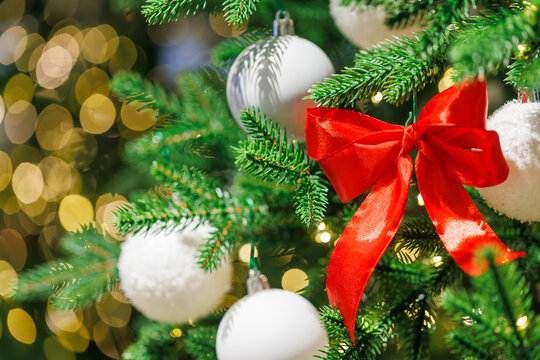 Red bow on Christmas tree with festive golden lights