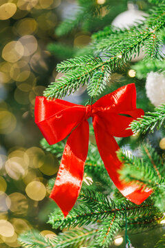 Red bow on Christmas tree with festive golden lights
