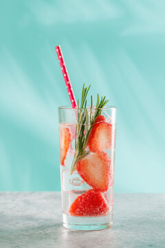 Fresh strawberry infused water with herbs on blue background with copy space