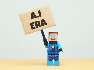 Fototapeta premium Indonesia - May 30, 2026 : Mini toy of action figure at table with blur background. Miniature photography concept design. Minifigure of Robot character hold Artificial Intelligence era text at poster.