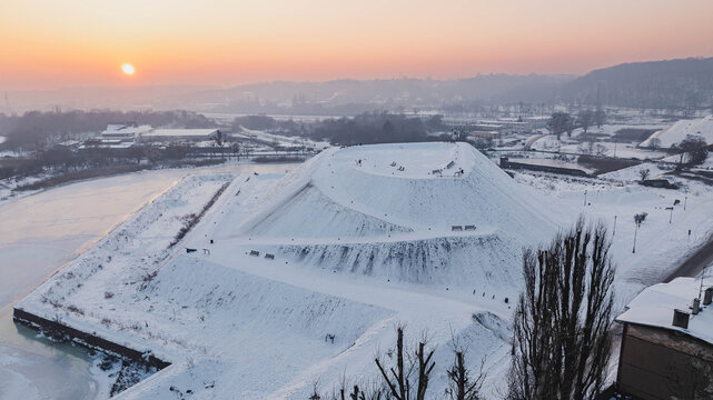 Aerial view of the historic bastions in Gdańsk, Poland, covered in snow at sunrise, with a frozen waterway and winter landscape.