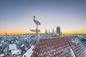 Aerial view of snowy Gdańsk, Poland, at sunset, showing the frozen Motława River, historic waterfront, Old Town and illuminated buildings. © Kamil