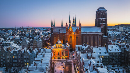 Aerial view of historic Gdańsk, Poland, with the snow-covered Old Town and St. Mary’s Basilica at sunset. © Kamil
