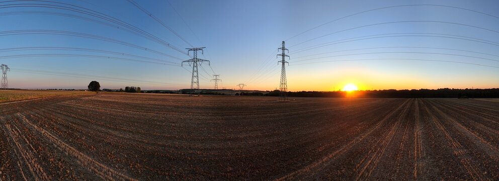 vue a&eacute;rienne panoramique sur des pyl&ocirc;nes &eacute;lectriques dans des champs, &agrave; la campagne.  Les c&acirc;bles sont arrondis avec l'effet grand angulaire de l'objectif. Ambiance  coucher de soleil.  France 2026