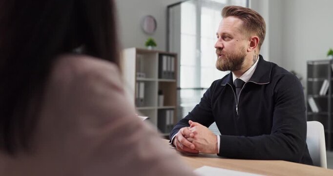 Interview, candidate, recruiter, interviewer discussing hiring resume. In a bright office meeting HR reviews CV while speaking calmly, gesturing. Concept of professional hiring and recruitment.