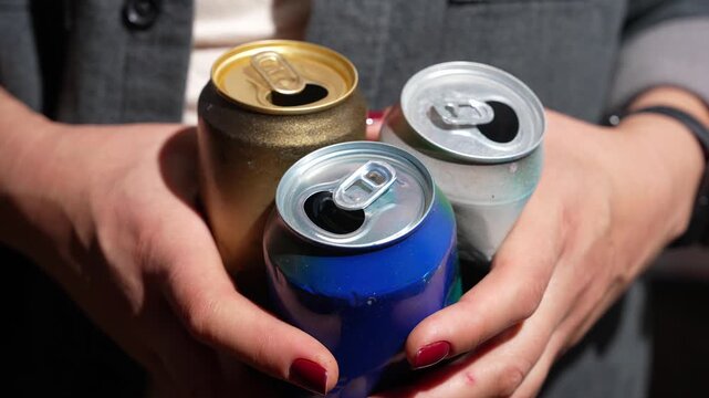 Woman with empty drink cans showing consumption waste