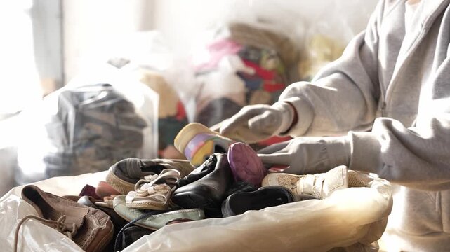 Person collecting fast fashion shoe and clothing waste. Clothing and shoe waste crisis