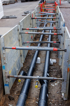 New modern insulated urban pipeline installation construction site  exposed underground pipes in shored trenches. Insulated steel pipes lie connection engineering infrastructure upgrade work