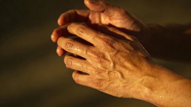 Close-Up of Wet Veiny Hands Under Warm Cinematic Lighting