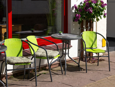 Outdoor Cafe Seating with Green Chairs, Tables and Blooming Purple Roses