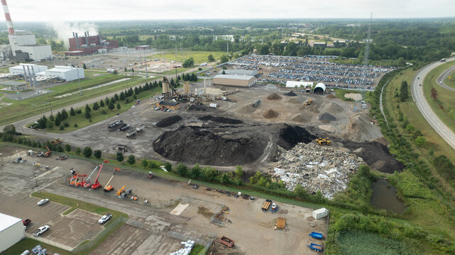 Aerial view of the Lansing Asphalt Terminal Co with piles of aggregate, construction machinery, and a large parking lot in Lansing, Michigan, United States.