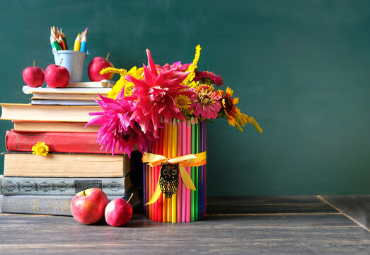 stack of learning books, school stationery, apples, flowers bouquet on table. beginning of the school year, Teacher's day, Knowledge Day, education, back to school, 1 September concept. copy space