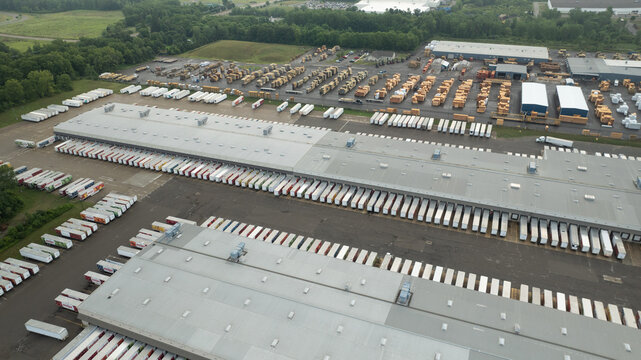 Aerial view of Meijer Distribution Center - DC 93 with numerous semi-trailers at loading docks, large warehouse rooftops, and surrounding green landscape in Lansing, Michigan, United States.