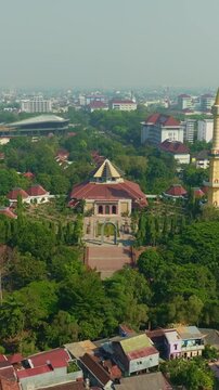 Mosque and minaret rising above green urban Yogyakarta cityscape