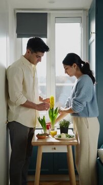 Young Iranian couple arranges a tasteful Haft-Seen display in a compact European apartment, combining hyacinth and apples with contemporary diaspora lifestyle and natural window light.