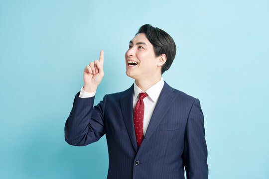 人差し指を立ててひらめくスーツ姿の男性