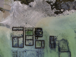 Aerial drone view of underwater oyster farms in Cancale, Brittany, exposed during low tide, raditional sustainable aquaculture and production of premium French oysters, France © barmalini
