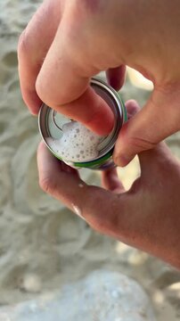 Opening a can of a foamy beverage