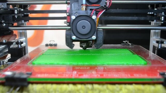 3D printer printing green model. Object printed on 3D printer from molten plastic green color. 3D printed object made from molten green plastic. Additive modern manufacturing. 3D printing technology
