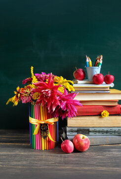 Stack of learning books, school stationery, apples, flowers bouquet on wooden table. beginning of the school year, Teacher's day, Knowledge Day, education, back to school, 1 September concept.