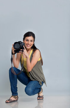 Portrait of smiling female photographer with camera in her studio 