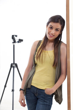 Portrait of young photographer leaning against wall in her studio 