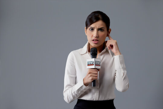 Portrait of news reporter listening against colored background 