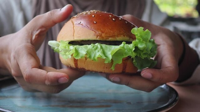 Holding a burger with lettuce at a cafe