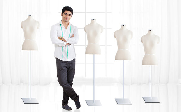 Full length of young male fashion designer standing by mannequin at studio 
