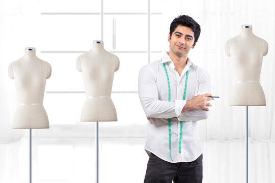 Handsome male fashion designer standing by mannequin at studio 