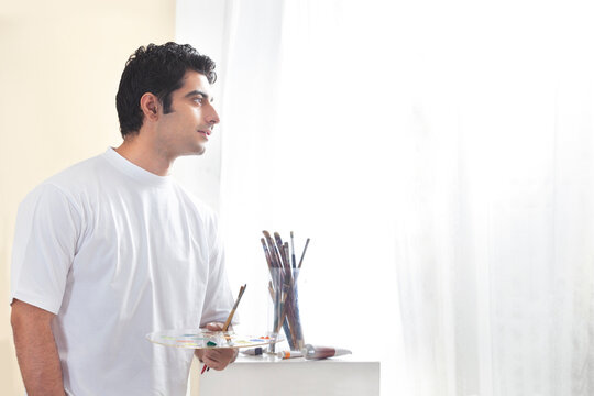 Male painter holding paint palette and brush 