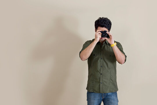 Young man using camera over colored background 